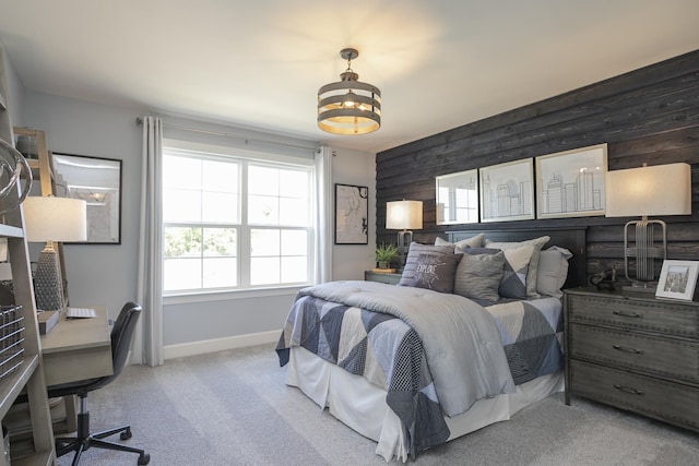 bedroom with light carpet, wood walls, and baseboards