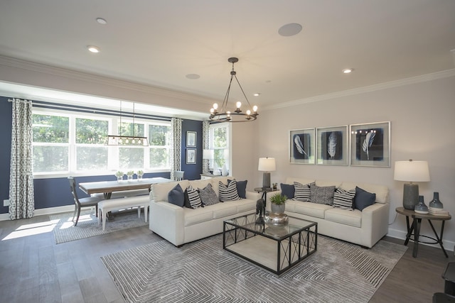 living room featuring baseboards, ornamental molding, wood finished floors, a chandelier, and recessed lighting