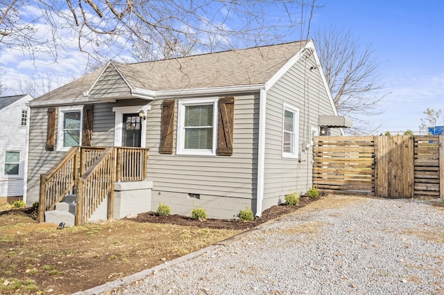 bungalow-style home featuring crawl space, fence, gravel driveway, and roof with shingles