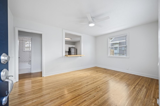 unfurnished living room with wood finished floors, a ceiling fan, and baseboards