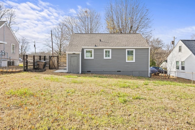 rear view of house featuring a yard, crawl space, fence, and a shingled roof