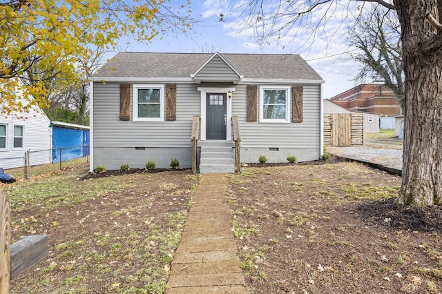 bungalow-style home featuring crawl space, fence, and roof with shingles