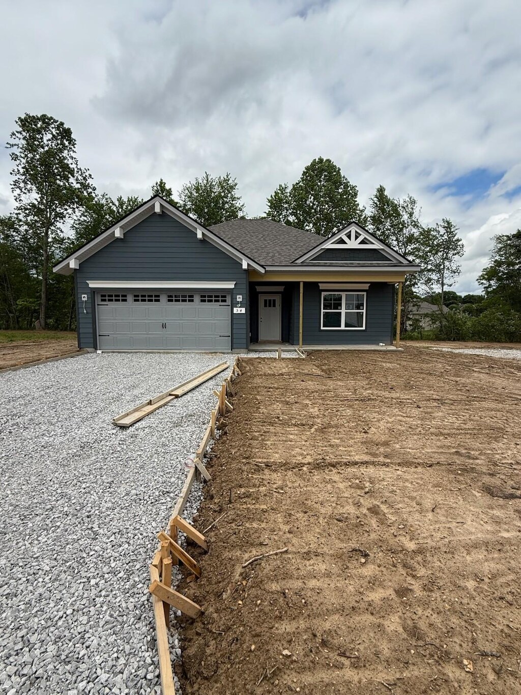 view of front of property with an attached garage, roof with shingles, and gravel driveway