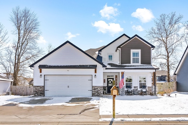 view of front of house featuring stone siding, covered porch, fence, and an attached garage