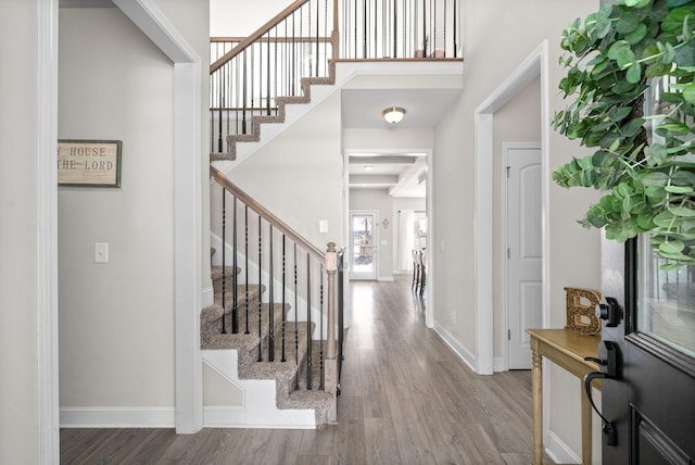 foyer featuring stairs, a high ceiling, wood finished floors, and baseboards