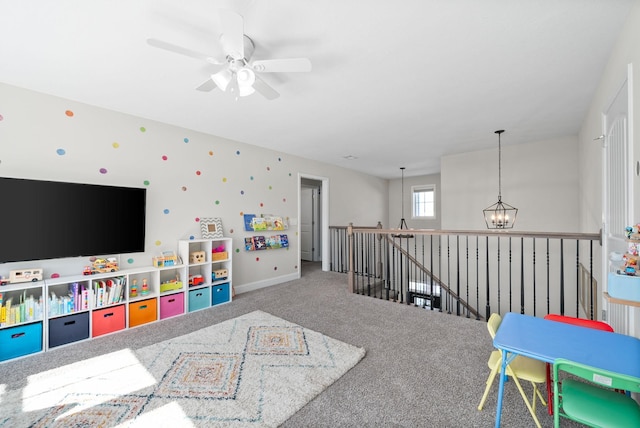 rec room featuring carpet floors, baseboards, and ceiling fan with notable chandelier