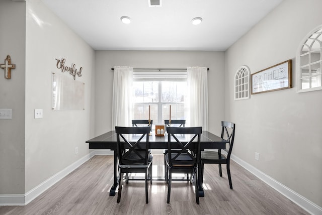 dining room with light wood-type flooring, visible vents, and baseboards