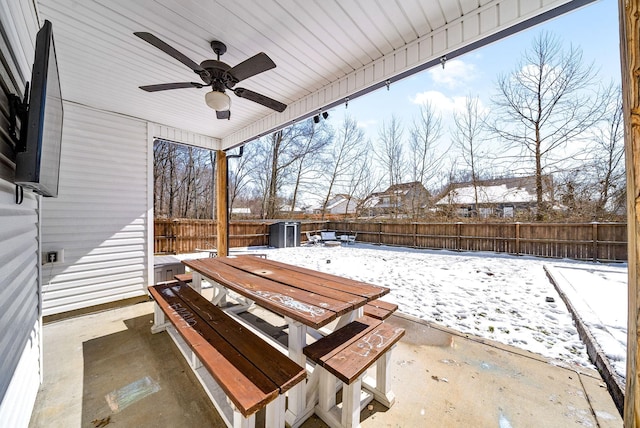 snow covered patio featuring a fenced backyard and a ceiling fan