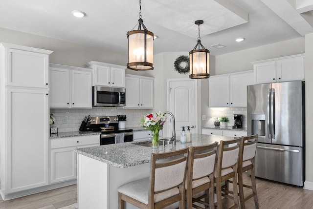 kitchen with stainless steel appliances, a sink, white cabinetry, and pendant lighting