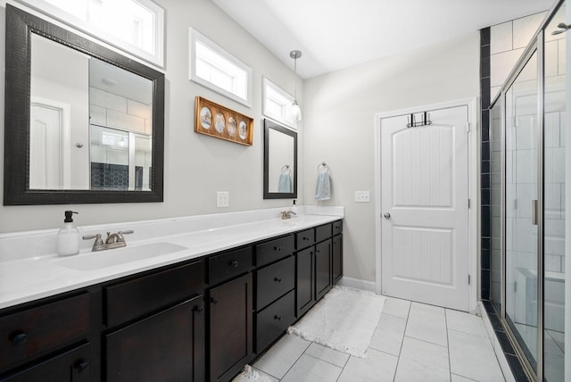 bathroom with double vanity, tile patterned flooring, a shower stall, and a sink