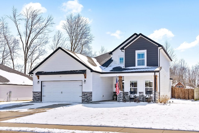 traditional home with stone siding, a porch, an attached garage, and fence