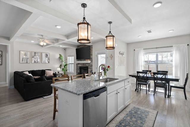 kitchen with light stone counters, white cabinetry, open floor plan, hanging light fixtures, and stainless steel dishwasher