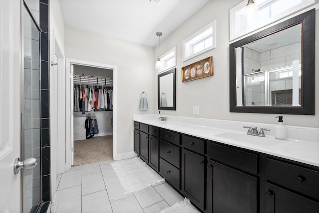 bathroom with a sink, a spacious closet, a shower stall, tile patterned floors, and double vanity