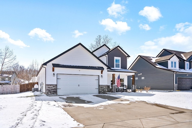 view of front of home featuring an attached garage, stone siding, and fence