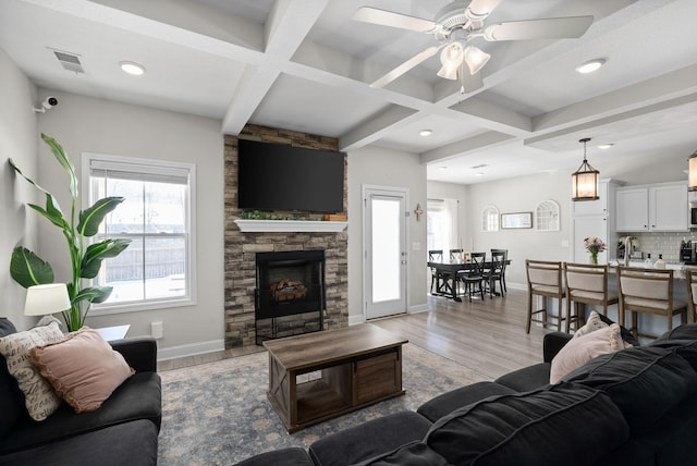 living room featuring light wood finished floors, coffered ceiling, and a healthy amount of sunlight