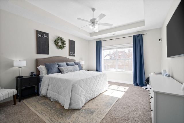 bedroom with a raised ceiling, light colored carpet, visible vents, and baseboards