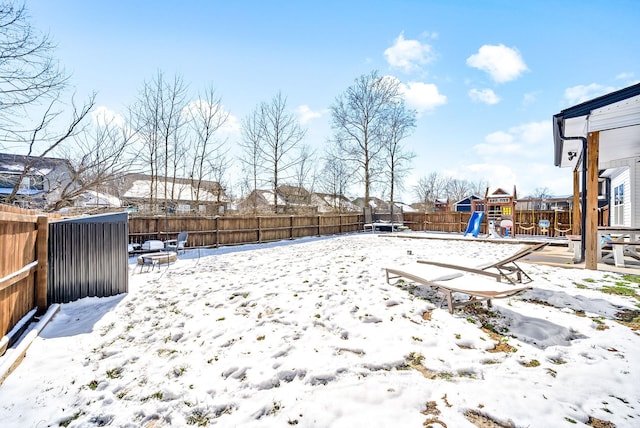 yard covered in snow with a fenced backyard and a playground