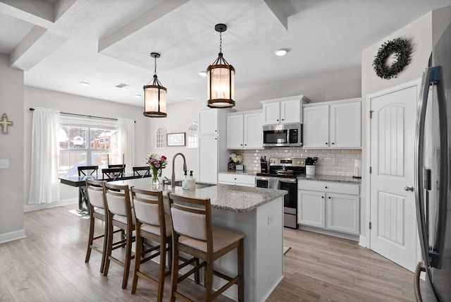 kitchen with appliances with stainless steel finishes, stone counters, white cabinetry, and pendant lighting