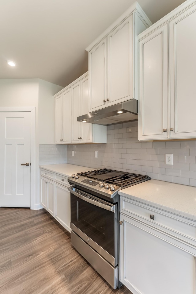 kitchen with light wood-type flooring, white cabinets, stainless steel range with gas stovetop, and under cabinet range hood