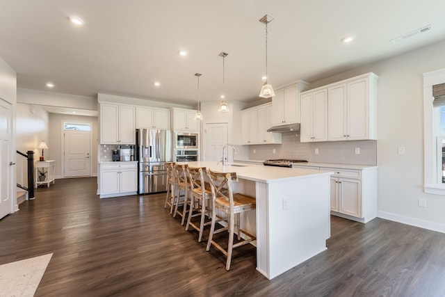 kitchen featuring tasteful backsplash, visible vents, stainless steel appliances, light countertops, and under cabinet range hood