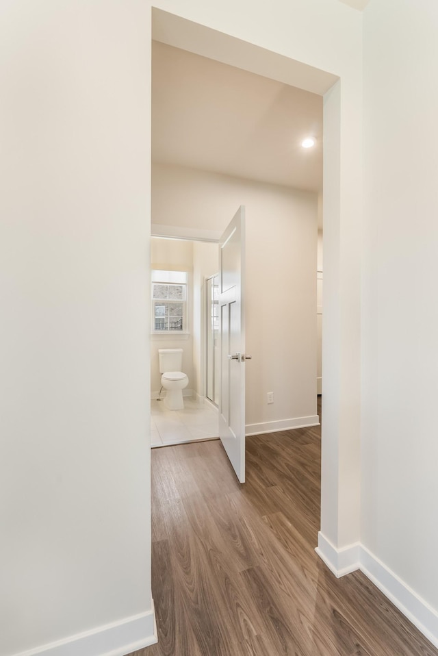 hall with baseboards and dark wood-type flooring