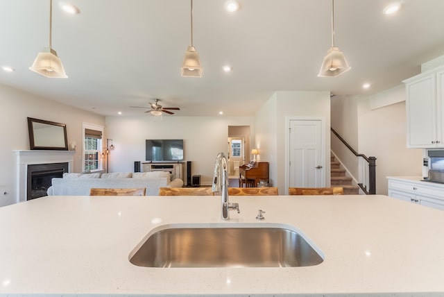 kitchen featuring open floor plan, decorative light fixtures, and a sink