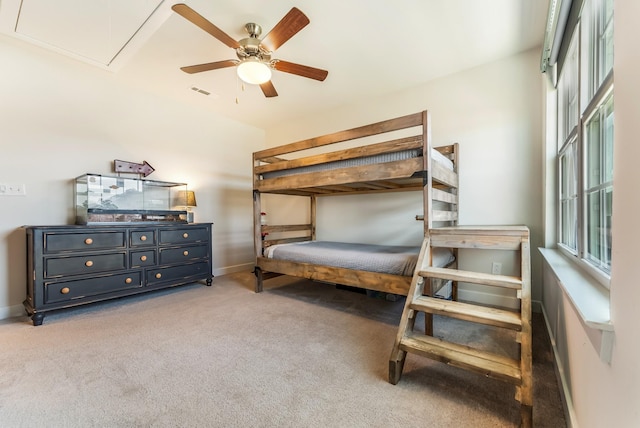 carpeted bedroom featuring attic access, visible vents, baseboards, and a ceiling fan