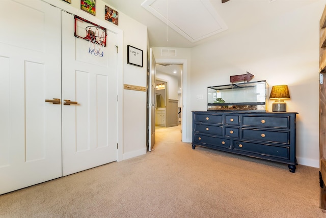 bedroom with attic access, light colored carpet, visible vents, and baseboards