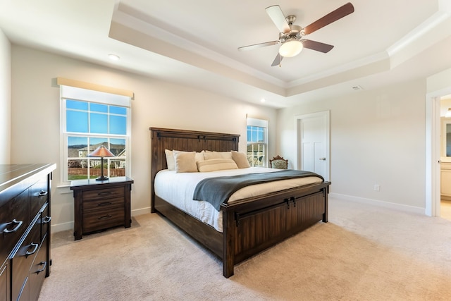 bedroom with baseboards, multiple windows, a raised ceiling, and light colored carpet