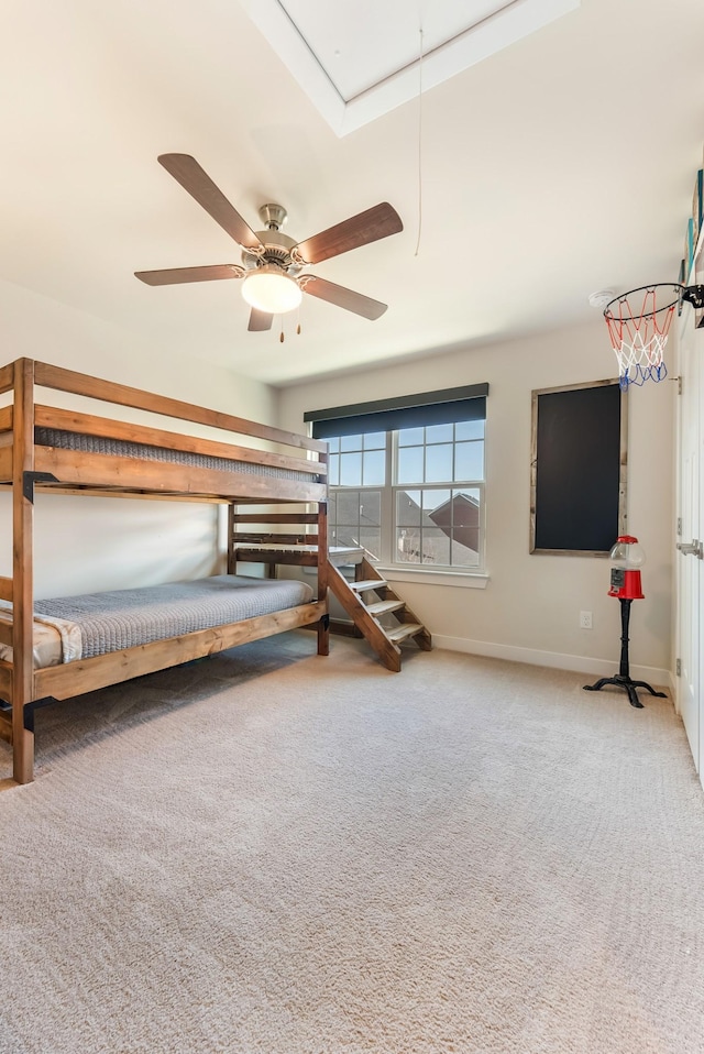 unfurnished bedroom with attic access, carpet flooring, baseboards, and a ceiling fan