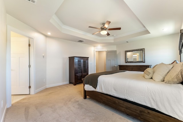 bedroom with ceiling fan, light colored carpet, visible vents, baseboards, and a raised ceiling