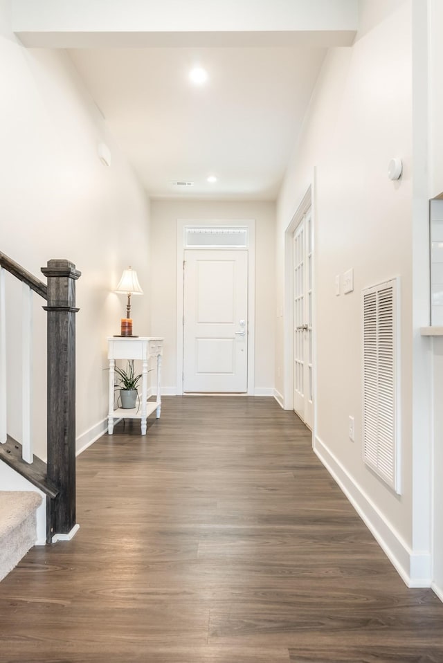 hall with stairs, dark wood-type flooring, visible vents, and baseboards