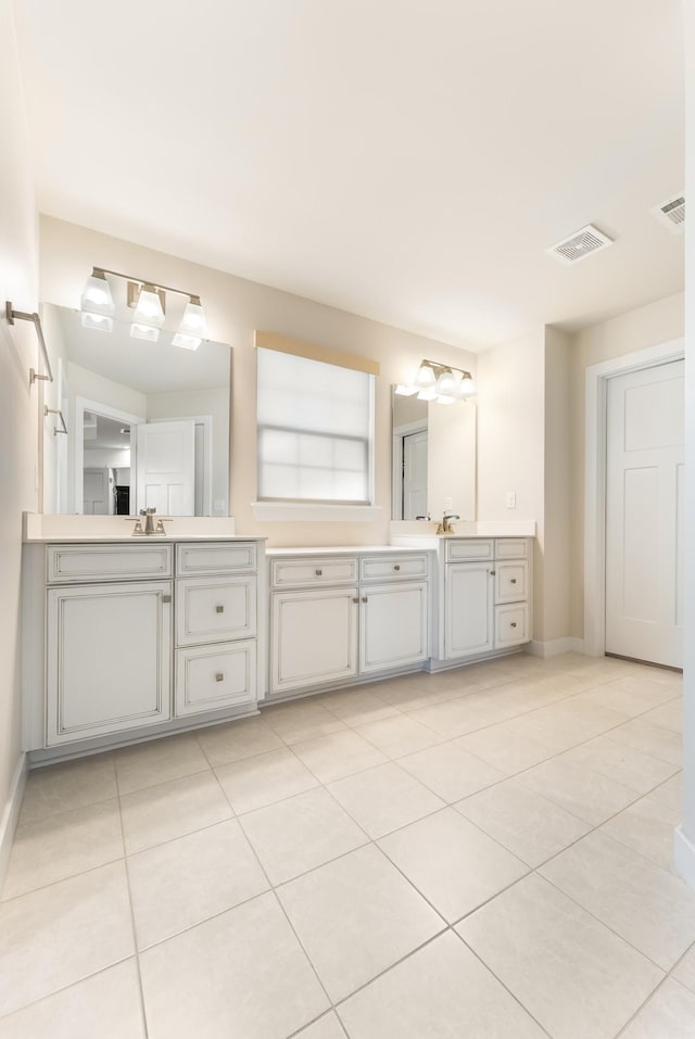 bathroom with double vanity, tile patterned flooring, visible vents, and baseboards