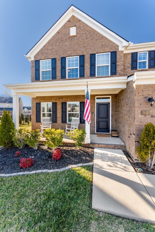 view of front of house featuring brick siding and a porch