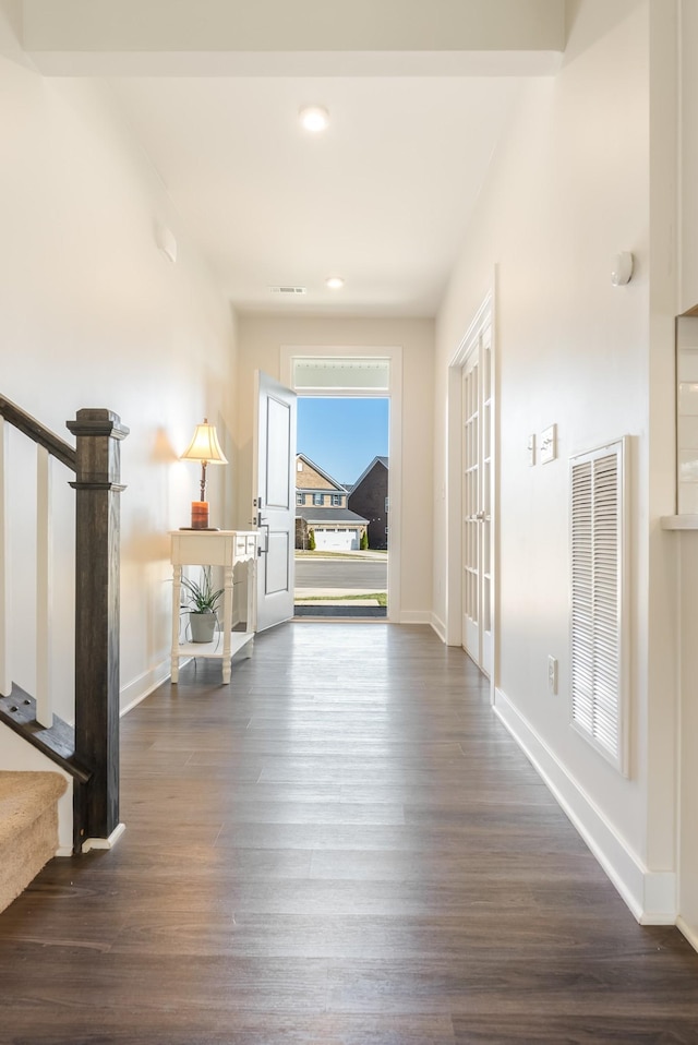 corridor featuring baseboards, stairs, visible vents, and dark wood-type flooring