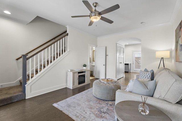 living room with ornamental molding, arched walkways, dark wood-style flooring, and stairs