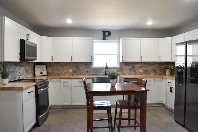 kitchen with black range with electric stovetop, a sink, refrigerator with ice dispenser, finished concrete flooring, and stainless steel microwave