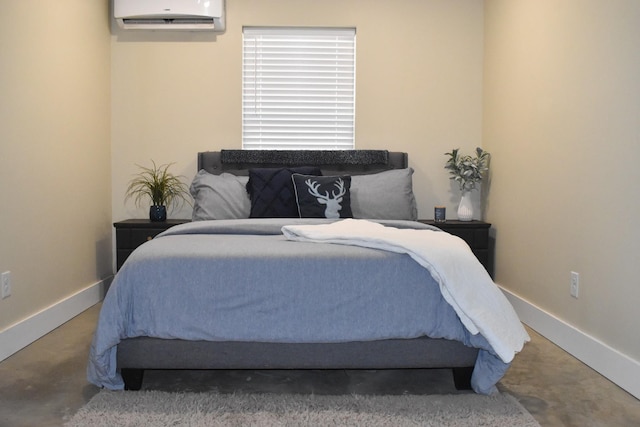 bedroom featuring a wall unit AC, baseboards, and concrete flooring