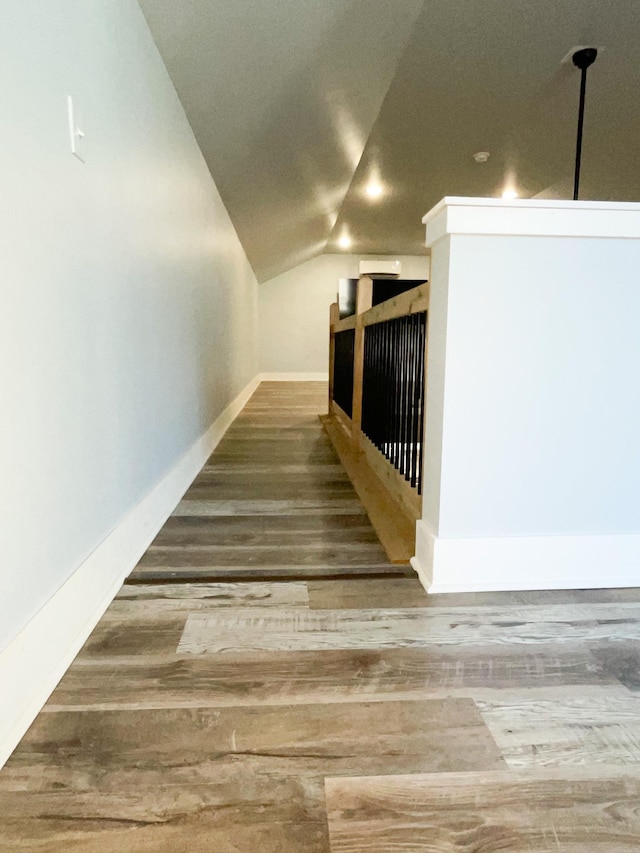 staircase with lofted ceiling, baseboards, and wood finished floors