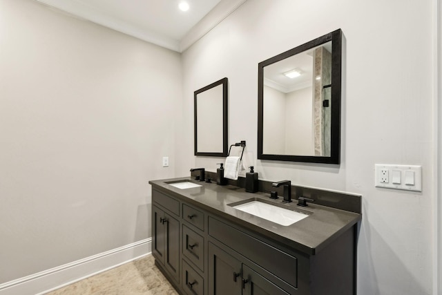 full bath with baseboards, double vanity, a sink, and crown molding