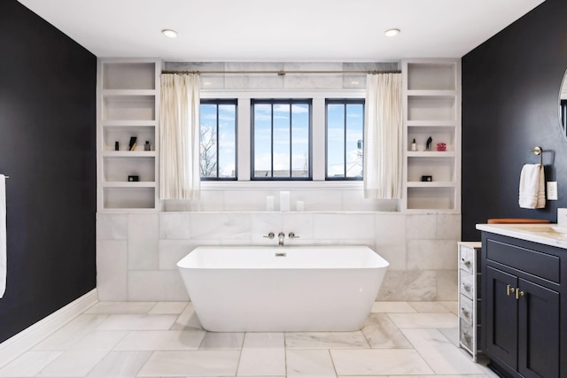 bathroom with built in features, a freestanding bath, and vanity