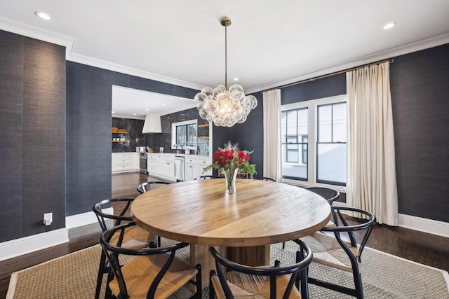 dining area with an inviting chandelier, baseboards, dark wood-style flooring, and ornamental molding