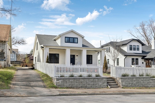 bungalow-style house with a fenced front yard, a porch, and a shingled roof