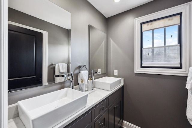 full bathroom featuring double vanity, baseboards, and a sink