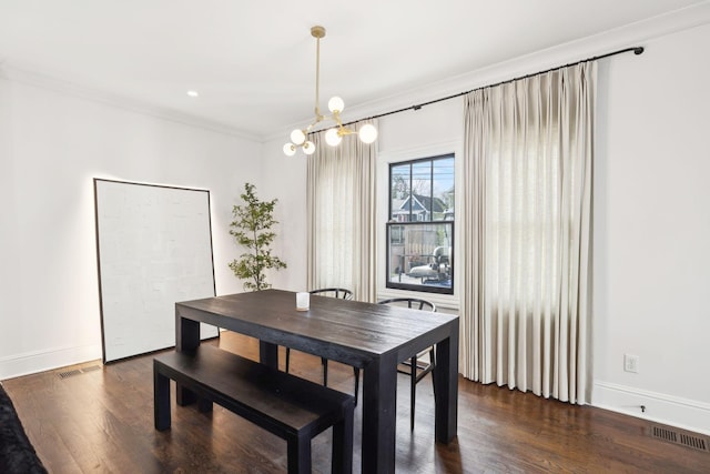 dining area with dark wood finished floors, visible vents, an inviting chandelier, ornamental molding, and baseboards