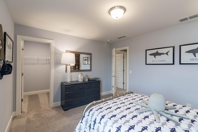 bedroom featuring visible vents, light carpet, baseboards, and a spacious closet