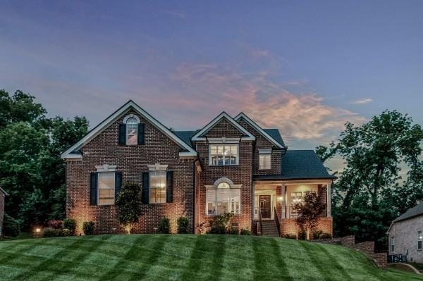 view of front of house with brick siding and a front lawn