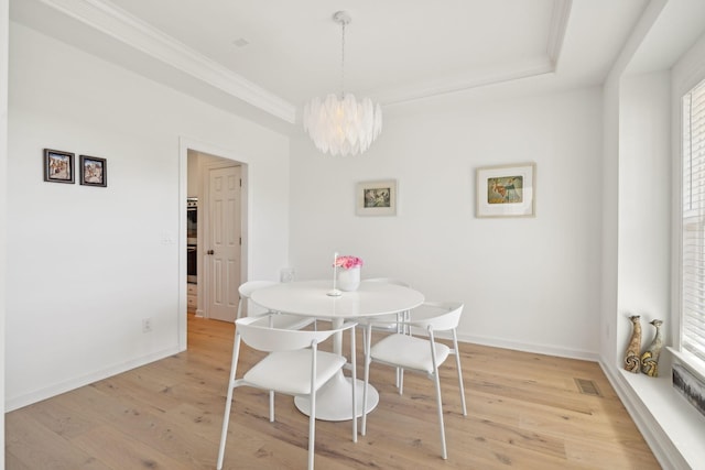 dining space featuring baseboards, visible vents, ornamental molding, an inviting chandelier, and light wood-type flooring