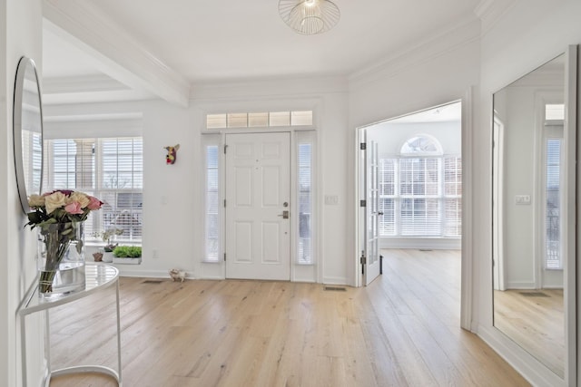 entrance foyer with ornamental molding, beamed ceiling, and light wood-style flooring