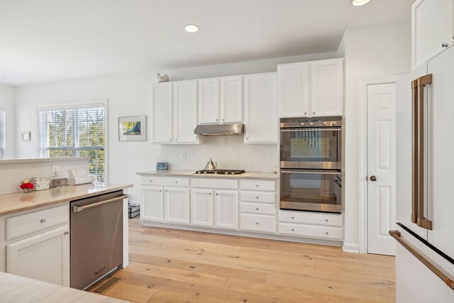 kitchen with light countertops, under cabinet range hood, white cabinetry, and stainless steel appliances